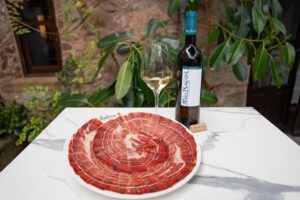 Plato jamón DOP Los Pedroches y albariño D.O. Rías Baixas sobre mesa de mármol