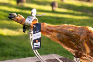 Pata de jamón ibérico de bellota 100% DOP Los Pedroches con vitola y cerdo al fondo