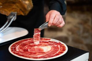 Maestro cortador emplatando lonchas de jamón ibérico DOP Los Pedroches con pinzas